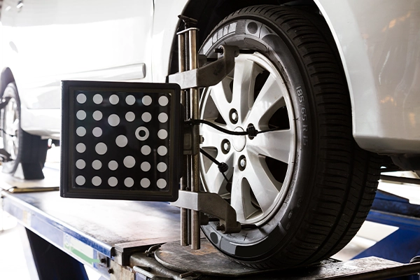 White SUV on wheel alignment rack