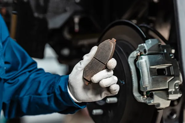 technician holding a replacement brake pad 